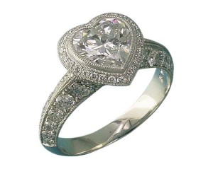 'Heartfelt' halo setting for heart-shape diamond. The metal takes a 'back seat' to the diamonds' brilliance. The beads for the pavé can be more delicate and subtle than would be necessary with white gold and the stones are set very securely.