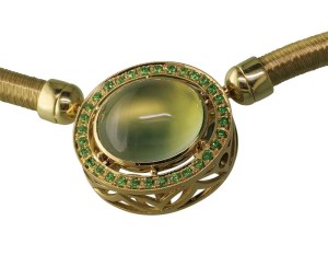 A green gold pendant featuring a bezel-set prehnite with demantoid garnets.