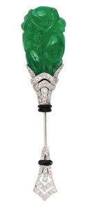 Platinum and 18-karat gold art deco jabot pin circa 1920s, with a vase motif set with round diamonds  and black enamel trim. The carved jadeite plaque depicts fruits amid foliage.