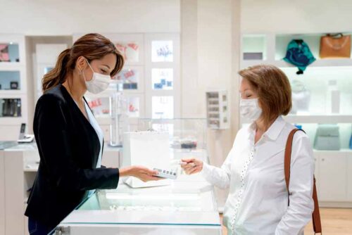 Woman buying jewellery while wearing a mask. 