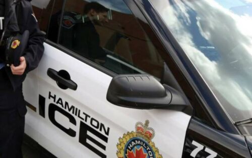 Officer leaning on a Hamilton Police vehicle. 